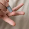 Applying a blood drop to a glucometer strip during a home sugar test