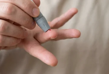 Applying a blood drop to a glucometer strip during a home sugar test