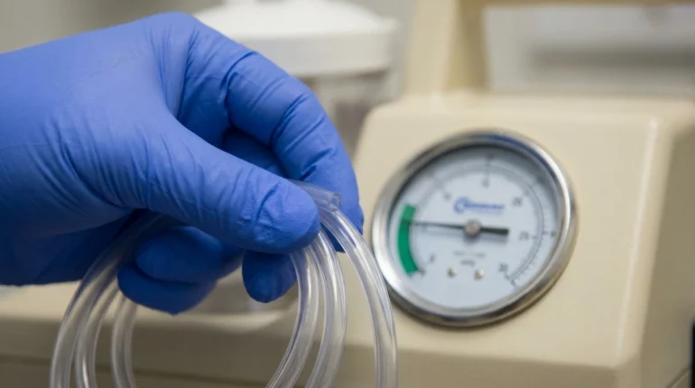 Caregiver checking the suction pressure gauge with the tubing pinched before use