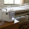 Portable medical suction machine set up beside a patient’s bed at home
